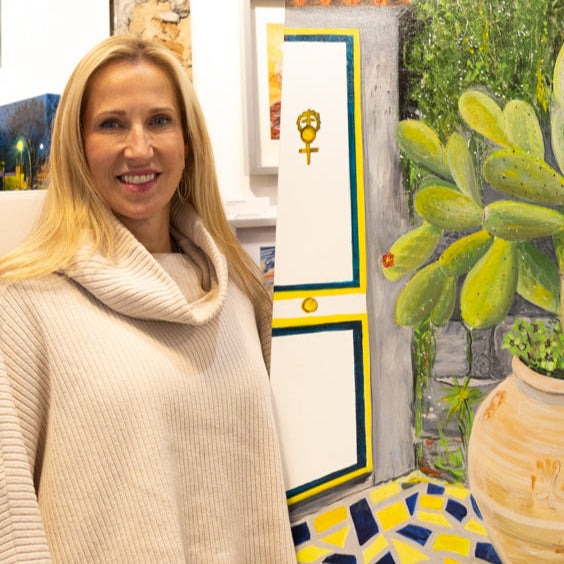 Artist, Sue Muri next to bright acrylic painting of flowering cactus in pot
