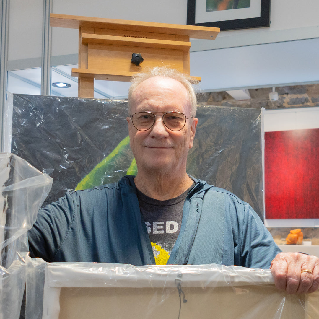 Alan Forster, fine artist, posing int eh PMAC studio with his work. 