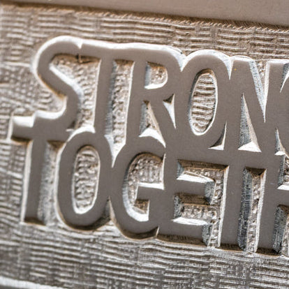 Slate carving that reads 'stronger together'.