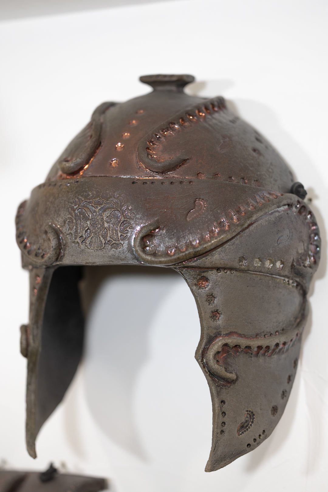 Broken Warrior by Brenda Sutton Mader: a dark, weathered ceramic helmet modelled on ornate historical armour.